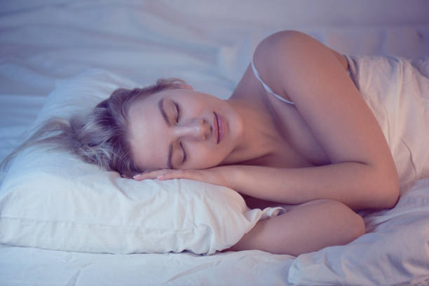 istock sleeping girl on an orthopedic pillow with night lighting, white linens 1150074507