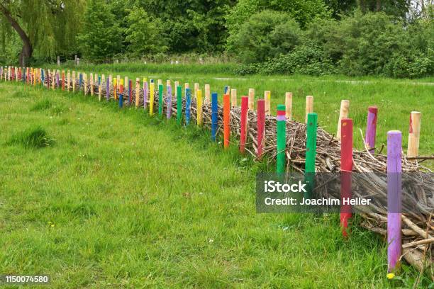 A Filled Fence Made Of Colorfully Painted Round Timber Palisades Creative Example Of A Community Garden Designed By Children Stock Photo - Download Image Now