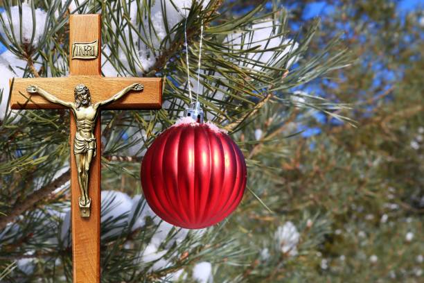 istock Red Christmas decoration hanging from outdoor tree with crucifix 1150078266