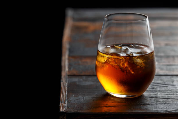 istock Glass of whiskey with ice on rustic table 1150078487