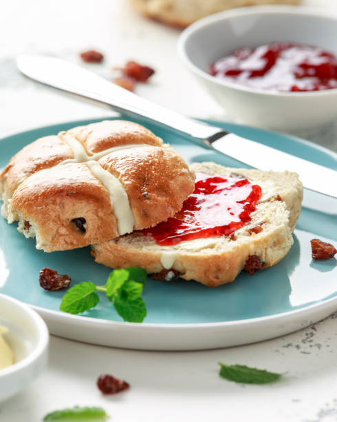 istock Hot cross buns in blue plate served with butter, strawberry jam and cup of tea 1150079110