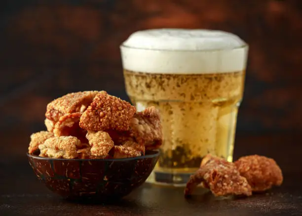 Photo of Crispy Pork scratchings with cold beer in bowl