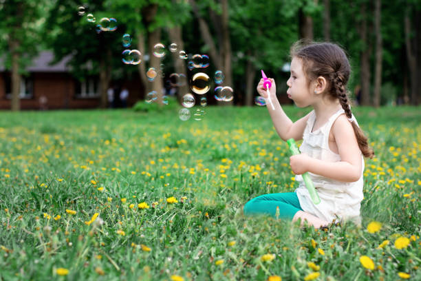istock Little girl blows soap bubbles in the park 1150082654