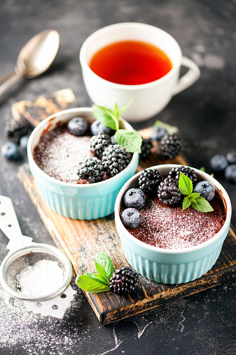 Healthy breakfast or snack. Chocolate mug cupcake with blueberries and blackberry in a blue ceramic mugs on a dark background.