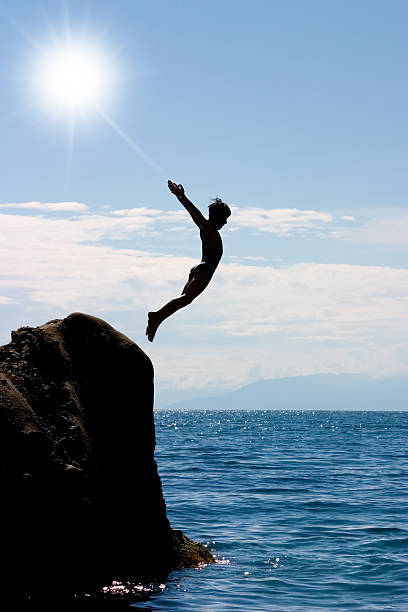 istock boy jumping to the sea 115008671