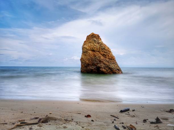 Beautiful single rock formation on the seashore with silky smooth water reflection background in Kuala Penyu Sabah. Borneo. A beautiful outdoor nature photography with a single rock formation on the seashore with silky smooth water reflection background. penyu kuala stock pictures, royalty-free photos & images