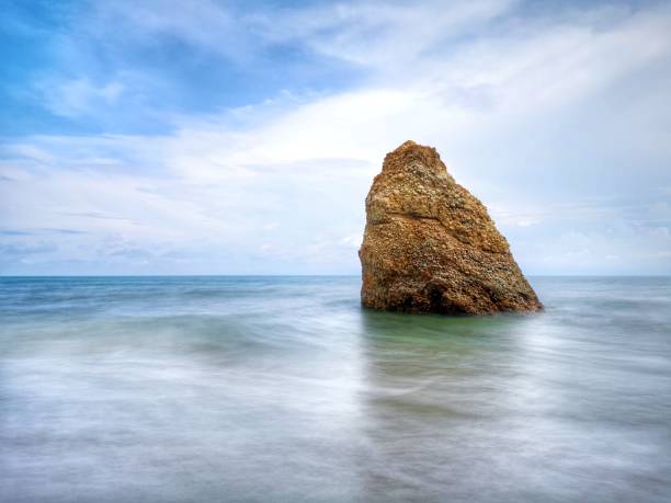 Beautiful single rock formation on the seashore with silky smooth water reflection background in Kuala Penyu Sabah. Borneo. A beautiful outdoor nature photography with a single rock formation on the seashore with silky smooth water reflection background. penyu kuala stock pictures, royalty-free photos & images