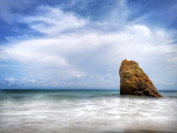 Beautiful single rock formation on the seashore with silky smooth water reflection background in Kuala Penyu Sabah. Borneo. A beautiful outdoor nature photography with a single rock formation on the seashore with silky smooth water reflection background. penyu kuala stock pictures, royalty-free photos & images
