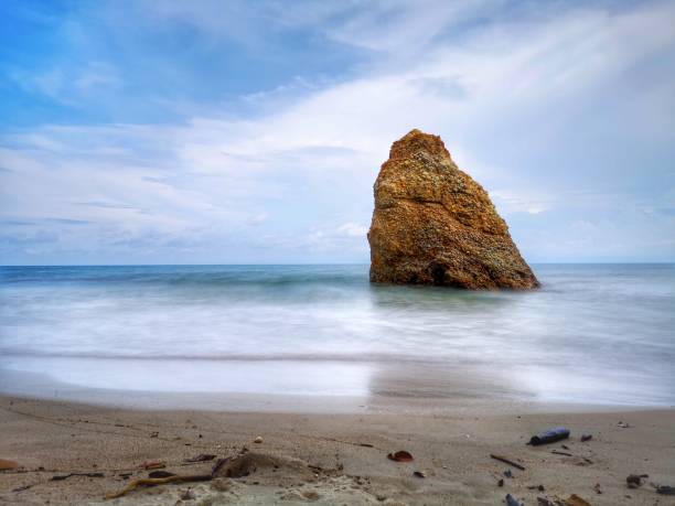 Beautiful single rock formation on the seashore with silky smooth water reflection background in Kuala Penyu Sabah. Borneo. A beautiful outdoor nature photography with a single rock formation on the seashore with silky smooth water reflection background. penyu kuala stock pictures, royalty-free photos & images