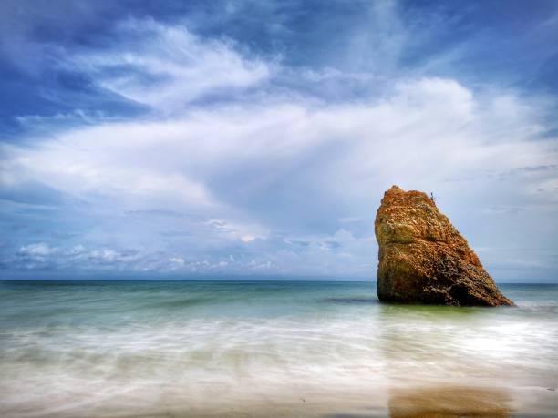 bella formazione rocciosa singola sulla riva del mare con sfondo setoso e liscio riflesso dell'acqua a kuala penyu sabah. borneo. - reflection water rock beach foto e immagini stock