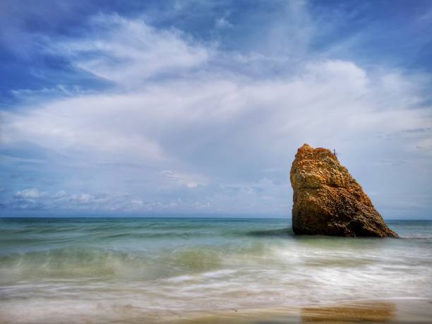 bella formazione rocciosa singola sulla riva del mare con sfondo setoso e liscio riflesso dell'acqua a kuala penyu sabah. borneo. - reflection water rock beach foto e immagini stock