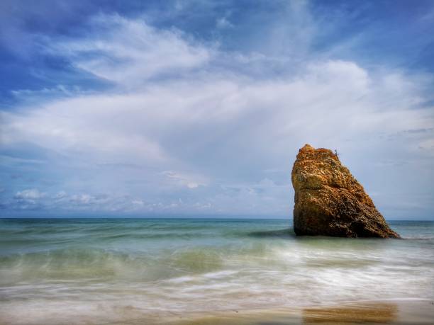 Beautiful single rock formation on the seashore with silky smooth water reflection background in Kuala Penyu Sabah. Borneo. A beautiful outdoor nature photography with a single rock formation on the seashore with silky smooth water reflection background. penyu kuala stock pictures, royalty-free photos & images