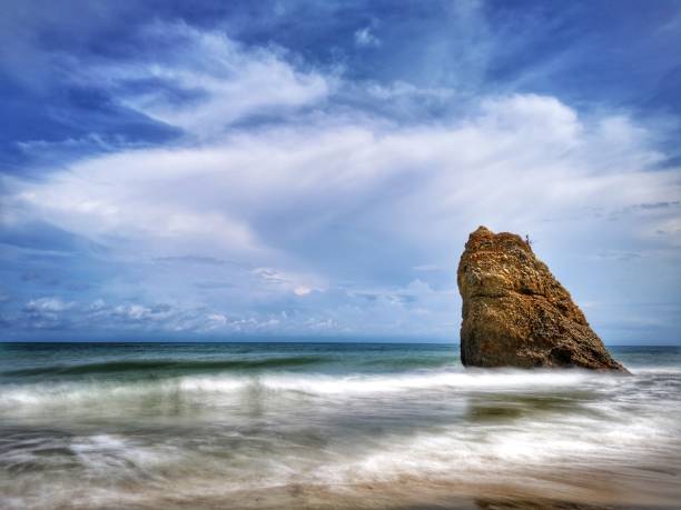 Beautiful single rock formation on the seashore with silky smooth water reflection background in Kuala Penyu Sabah. Borneo. A beautiful outdoor nature photography with a single rock formation on the seashore with silky smooth water reflection background. penyu kuala stock pictures, royalty-free photos & images