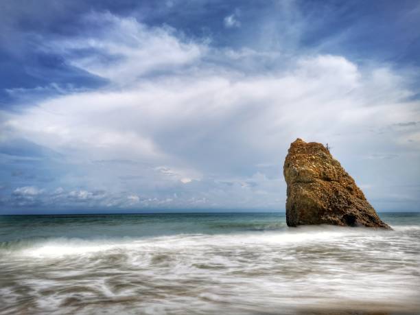 Beautiful single rock formation on the seashore with silky smooth water reflection background in Kuala Penyu Sabah. Borneo. A beautiful outdoor nature photography with a single rock formation on the seashore with silky smooth water reflection background. penyu kuala stock pictures, royalty-free photos & images