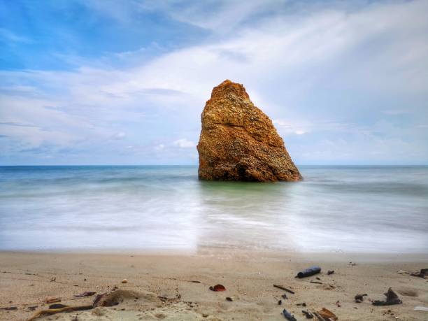 Beautiful single rock formation on the seashore with silky smooth water reflection background in Kuala Penyu Sabah. Borneo. A beautiful outdoor nature photography with a single rock formation on the seashore with silky smooth water reflection background. penyu kuala stock pictures, royalty-free photos & images