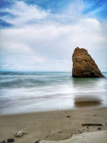 Beautiful single rock formation on the seashore with silky smooth water reflection background in Kuala Penyu Sabah. Borneo. A beautiful outdoor nature photography with a single rock formation on the seashore with silky smooth water reflection background. penyu kuala stock pictures, royalty-free photos & images