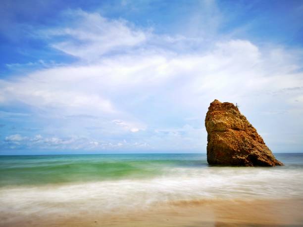 Beautiful single rock formation on the seashore with silky smooth water reflection background in Kuala Penyu Sabah. Borneo. A beautiful outdoor nature photography with a single rock formation on the seashore with silky smooth water reflection background. penyu kuala stock pictures, royalty-free photos & images