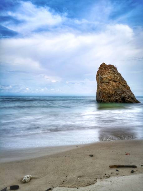 Beautiful single rock formation on the seashore with silky smooth water reflection background in Kuala Penyu Sabah. Borneo. A beautiful outdoor nature photography with a single rock formation on the seashore with silky smooth water reflection background. penyu kuala stock pictures, royalty-free photos & images