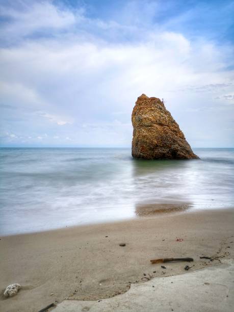 Beautiful single rock formation on the seashore with silky smooth water reflection background in Kuala Penyu Sabah. Borneo. A beautiful outdoor nature photography with a single rock formation on the seashore with silky smooth water reflection background. penyu kuala stock pictures, royalty-free photos & images