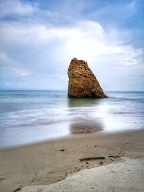 Beautiful single rock formation on the seashore with silky smooth water reflection background in Kuala Penyu Sabah. Borneo. A beautiful outdoor nature photography with a single rock formation on the seashore with silky smooth water reflection background. penyu kuala stock pictures, royalty-free photos & images