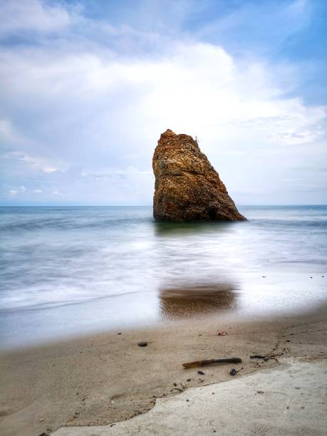 bella formazione rocciosa singola sulla riva del mare con sfondo setoso e liscio riflesso dell'acqua a kuala penyu sabah. borneo. - reflection water rock beach foto e immagini stock