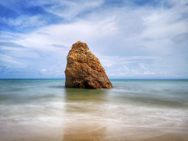 Beautiful single rock formation on the seashore with silky smooth water reflection background in Kuala Penyu Sabah. Borneo. A beautiful outdoor nature photography with a single rock formation on the seashore with silky smooth water reflection background. penyu kuala stock pictures, royalty-free photos & images