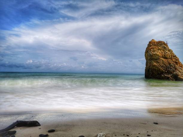 Beautiful single rock formation on the seashore with silky smooth water reflection background in Kuala Penyu Sabah. Borneo. A beautiful outdoor nature photography with a single rock formation on the seashore with silky smooth water reflection background. penyu kuala stock pictures, royalty-free photos & images
