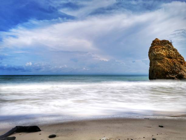 Beautiful single rock formation on the seashore with silky smooth water reflection background in Kuala Penyu Sabah. Borneo. A beautiful outdoor nature photography with a single rock formation on the seashore with silky smooth water reflection background. penyu kuala stock pictures, royalty-free photos & images