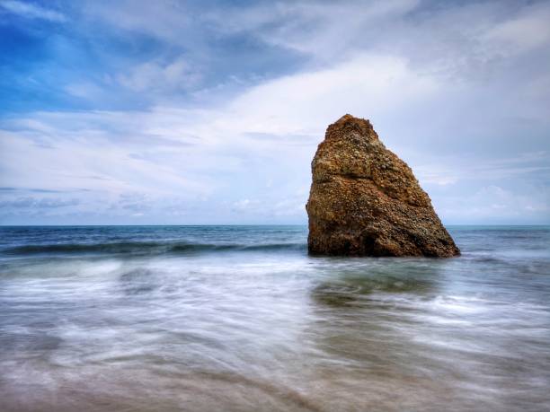 Beautiful single rock formation on the seashore with silky smooth water reflection background in Kuala Penyu Sabah. Borneo. A beautiful outdoor nature photography with a single rock formation on the seashore with silky smooth water reflection background. penyu kuala stock pictures, royalty-free photos & images