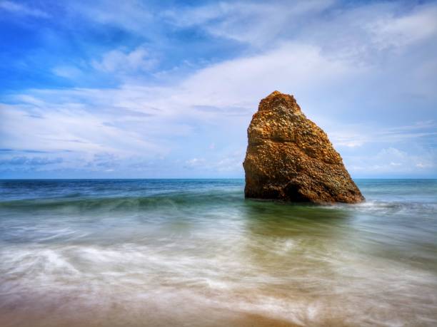 Beautiful single rock formation on the seashore with silky smooth water reflection background in Kuala Penyu Sabah. Borneo. A beautiful outdoor nature photography with a single rock formation on the seashore with silky smooth water reflection background. penyu kuala stock pictures, royalty-free photos & images