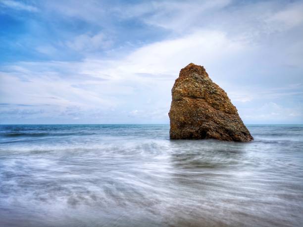 Beautiful single rock formation on the seashore with silky smooth water reflection background in Kuala Penyu Sabah. Borneo. A beautiful outdoor nature photography with a single rock formation on the seashore with silky smooth water reflection background. penyu kuala stock pictures, royalty-free photos & images