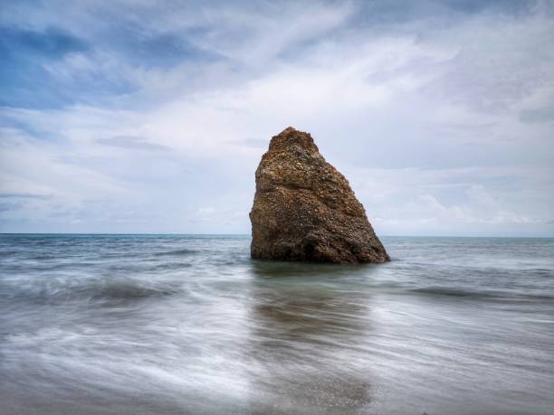 bella formazione rocciosa singola sulla riva del mare con sfondo setoso e liscio riflesso dell'acqua a kuala penyu sabah. borneo. - reflection water rock beach foto e immagini stock