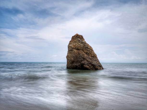 Beautiful single rock formation on the seashore with silky smooth water reflection background in Kuala Penyu Sabah. Borneo. A beautiful outdoor nature photography with a single rock formation on the seashore with silky smooth water reflection background. penyu kuala stock pictures, royalty-free photos & images
