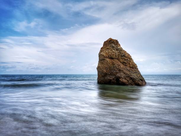 Beautiful single rock formation on the seashore with silky smooth water reflection background in Kuala Penyu Sabah. Borneo. A beautiful outdoor nature photography with a single rock formation on the seashore with silky smooth water reflection background. penyu kuala stock pictures, royalty-free photos & images