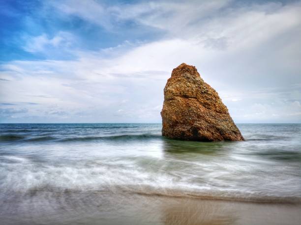Beautiful single rock formation on the seashore with silky smooth water reflection background in Kuala Penyu Sabah. Borneo. A beautiful outdoor nature photography with a single rock formation on the seashore with silky smooth water reflection background. penyu kuala stock pictures, royalty-free photos & images