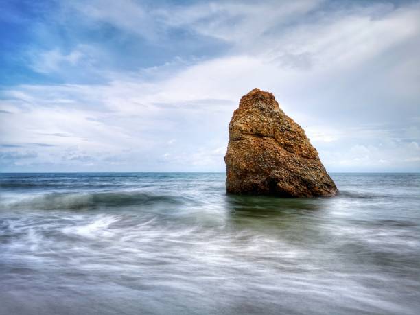 Beautiful single rock formation on the seashore with silky smooth water reflection background in Kuala Penyu Sabah. Borneo. A beautiful outdoor nature photography with a single rock formation on the seashore with silky smooth water reflection background. penyu kuala stock pictures, royalty-free photos & images