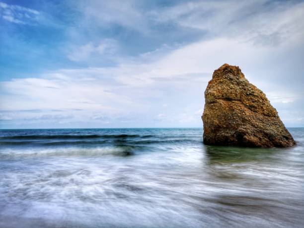 Beautiful single rock formation on the seashore with silky smooth water reflection background in Kuala Penyu Sabah. Borneo. A beautiful outdoor nature photography with a single rock formation on the seashore with silky smooth water reflection background. penyu kuala stock pictures, royalty-free photos & images