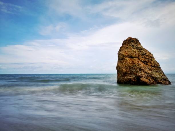 Beautiful single rock formation on the seashore with silky smooth water reflection background in Kuala Penyu Sabah. Borneo. A beautiful outdoor nature photography with a single rock formation on the seashore with silky smooth water reflection background. penyu kuala stock pictures, royalty-free photos & images