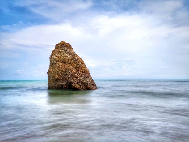 Beautiful single rock formation on the seashore with silky smooth water reflection background in Kuala Penyu Sabah. Borneo. A beautiful outdoor nature photography with a single rock formation on the seashore with silky smooth water reflection background. penyu kuala stock pictures, royalty-free photos & images