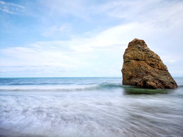 Beautiful single rock formation on the seashore with silky smooth water reflection background in Kuala Penyu Sabah. Borneo. A beautiful outdoor nature photography with a single rock formation on the seashore with silky smooth water reflection background. penyu kuala stock pictures, royalty-free photos & images