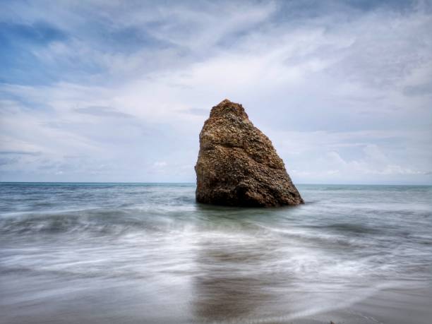 bella formazione rocciosa singola sulla riva del mare con sfondo setoso e liscio riflesso dell'acqua a kuala penyu sabah. borneo. - reflection water rock beach foto e immagini stock