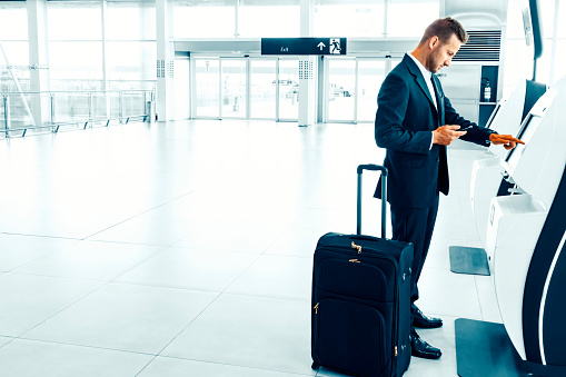 Photo of a young businessman at an airport making check in.