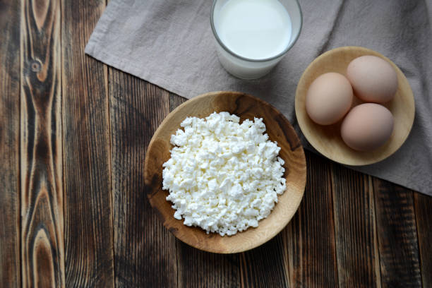 queso cottage en un tazón de madera, leche en un vaso, huevos. productos agrícolas. village breakfast - cottage cheese fotografías e imágenes de stock