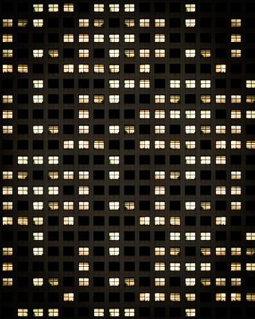 Windows lights in a high-rise apartment building at night.