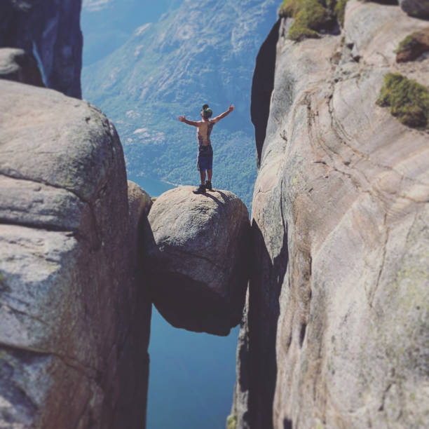 hiker standing on kjeragbolten in norway - kjeragbolten imagens e fotografias de stock