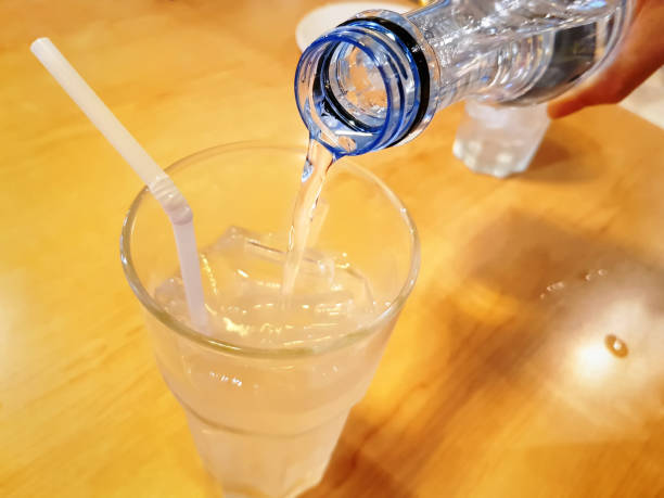 istock Pouring Mineral Drinking Water From Bottle Into Glass with Ice Cubes with Selective Focus 1150108430