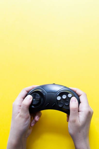 istock Vertical view to hands holding black gamepad and playing video game against yellow 1150111814