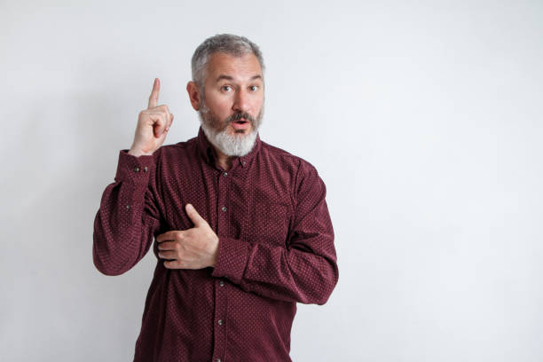 istock Portrait gray bearded man has an idea, pointing with index finger up isolated on white wall background 1150114287