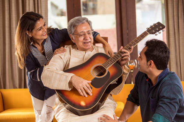 familie mit gitarre zu hause - group of people aging process home interior indoors stock-fotos und bilder