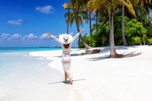 istock Woman walks on a tropical beach with white hat 1150117932